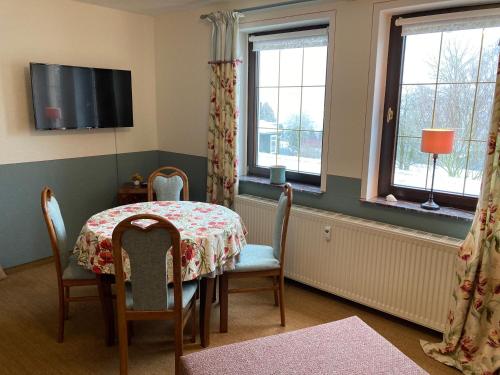 a dining room with a table and chairs and windows at Ferienwohnung Prüfer in Greiz