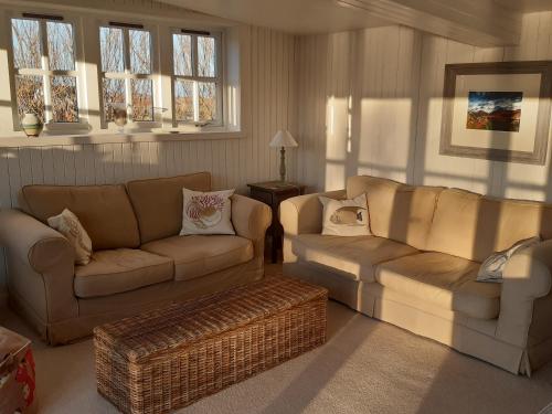 a living room with two couches and a table and windows at The Loan in Achiltibuie