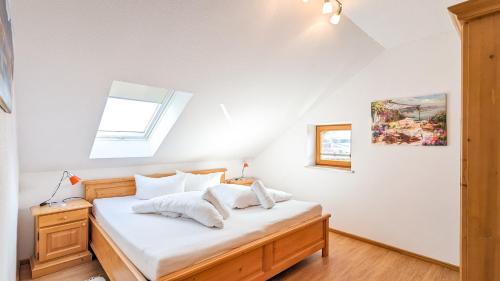 a bedroom with a bed with white sheets and a window at Ferienwohnung Forggensee in Roßhaupten