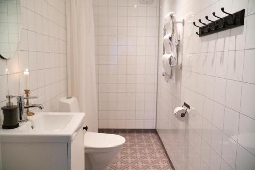 La salle de bains blanche est pourvue de toilettes et d'un lavabo. dans l'établissement Anfasteröd Gårdsvik - badstugor med loft, à Ljungskile