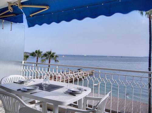 - une table avec des chaises et une vue sur l'océan dans l'établissement Résidence de la mer, à Juan-les-Pins