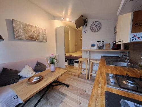 cocina y sala de estar con sofá y mesa en Joli studio au calme dans un jardin privatif, en Ouistreham