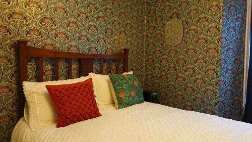 ein Bett mit roten und grünen Kissen in einem Schlafzimmer in der Unterkunft The Bear Bread Bakery, boutique en-suite rooms with breakfast in the Bakery, in the heart of Colyton in Colyton