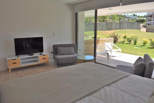 a bedroom with a television and a couch and a chair at SYRAH Premium B1 - Vistas al Parque by depptö in Punta del Este