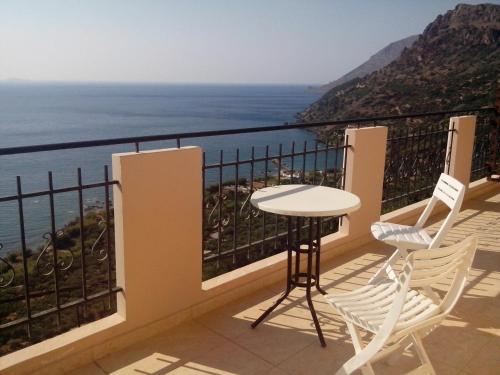 a balcony with a table and two chairs and the ocean at Kleio Studios in Ravdhoúkha
