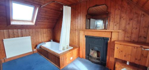 a bathroom with a tub and a fireplace in a cabin at The Loan in Achiltibuie