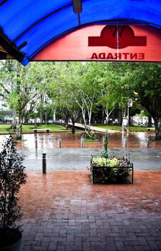 an umbrella over a bench in a park in the rain at Hotel R Williams in Puerto Francisco de Orellana