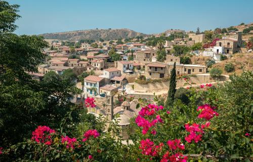 un pueblo en una colina con flores rosas en The Carob Tree Villa - 3 BR Rustic Luxury Home, en Lárnaca