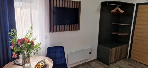 a room with a table with a vase of flowers and a television at M apartmani in Lukavica