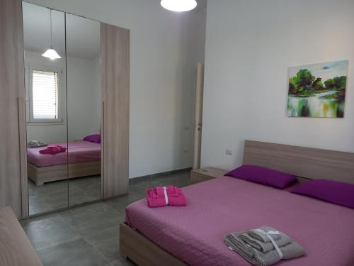 1 dormitorio con cama morada y espejo en Casa Beranu, en Maracalagonis