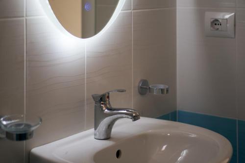 een wastafel in de badkamer met een kraan en een spiegel bij The Garrison Apartment in Sarandë