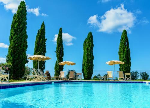 una piscina con sedie, ombrelloni e alberi di Appartamenti in Residence Villa Santa Maria a San Vincenzo