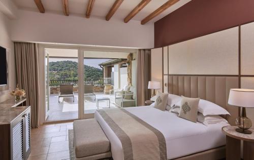 a bedroom with a large bed and a balcony at Conrad Chia Laguna Sardinia in Chia