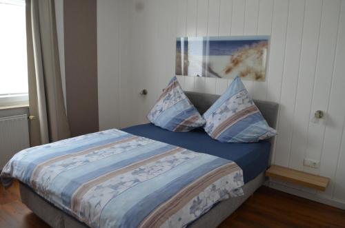 um quarto com uma cama com lençóis e almofadas azuis em Kutter im Schiffehaus em Wangerland
