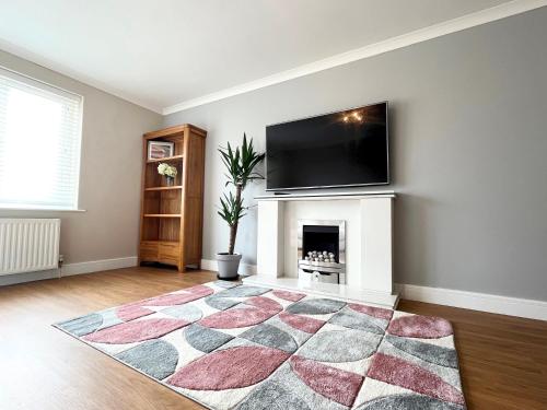 a living room with a fireplace and a flat screen tv at Modern 3 bed Bungalow with parking, private garden in Newlyn