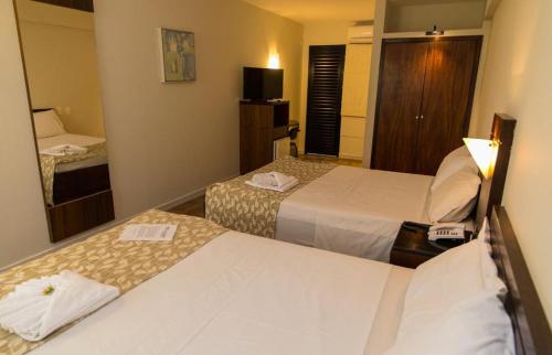 a hotel room with two beds and a television at Elo Hotels Express in Maringá
