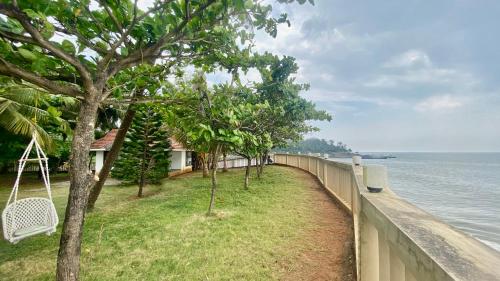 a fence next to the ocean with a swing at Willo stays The Metro Landsend Beach Resorts in Kannur
