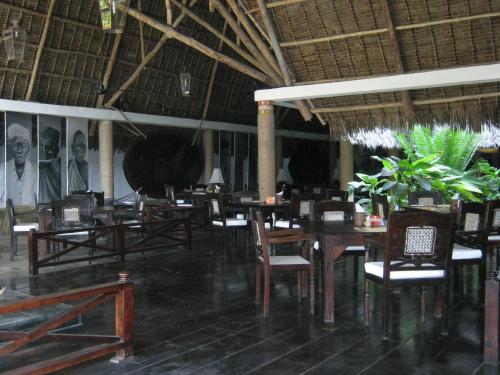 a dining room with tables and chairs and posters on the wall at Scorpio Villas Resort in Malindi