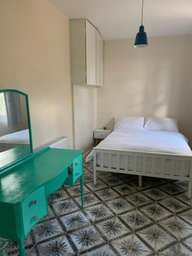 ein Schlafzimmer mit einem Bett und einem grünen Schreibtisch in der Unterkunft Fieldside Studio Flat in Hendon
