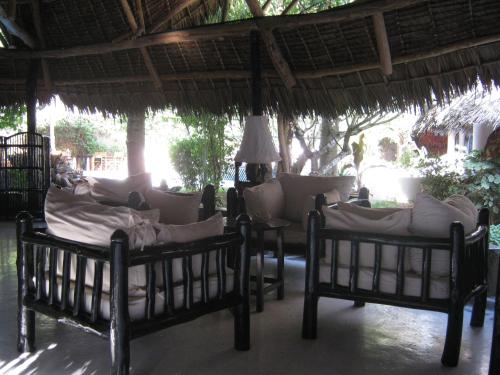 two beds sitting under a straw umbrella at Scorpio Villas Resort in Malindi