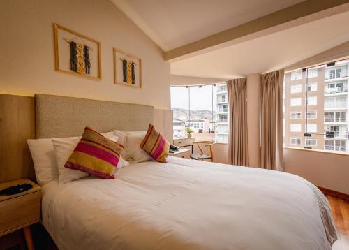 Schlafzimmer mit einem weißen Bett und einem großen Fenster in der Unterkunft Torre Dorada Cusco in Cusco