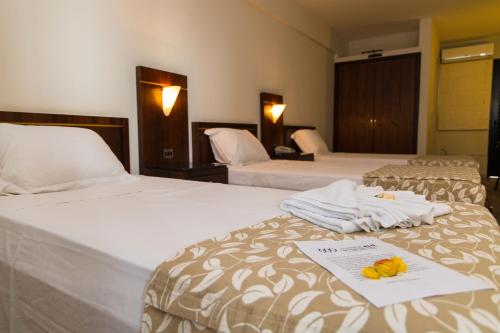 Habitación de hotel con 2 camas, toallas y menú en Elo Hotels Express, en Maringá