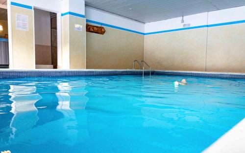 a person swimming in a large swimming pool at Hotel San Giusto in Falcade