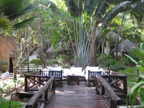 a wooden walkway with tables and chairs in a garden at Scorpio Villas Resort in Malindi