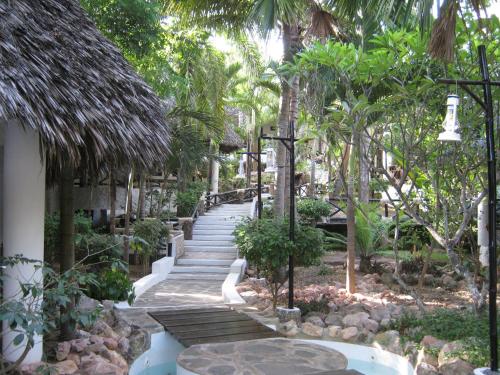 a walkway in a garden with palm trees at Scorpio Villas Resort in Malindi