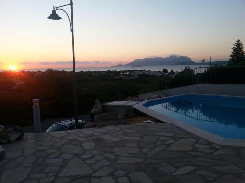 a swimming pool with the sunset in the background at Sardegna casa a 250 metri dal mare con piscina in Olbia