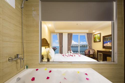 a bedroom with a bed and a tub and a mirror at Regalia Nha Trang in Nha Trang