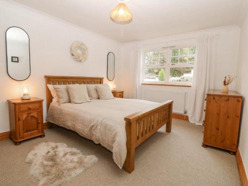 a bedroom with a bed with two night stands and a window at Bwthyn Clai in Llangefni