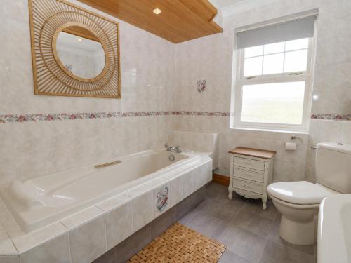 a bathroom with a tub and a toilet and a sink at Bwthyn Clai in Llangefni