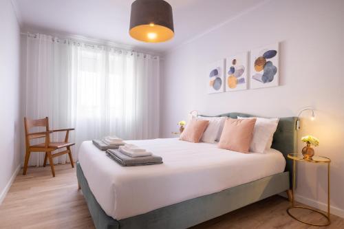 a bedroom with a large white bed and a chair at Hospitality is an Art - Ponta Delgada City Center in Ponta Delgada