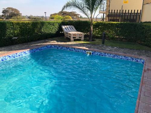 a swimming pool with a bench next to a house at LouieVille One Bedroom Apartment in Lusaka