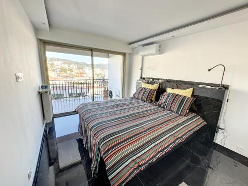 une chambre avec un lit et une grande fenêtre dans l'établissement SUQ3 - Très beau 2 pièces avec terrasse, à Cannes