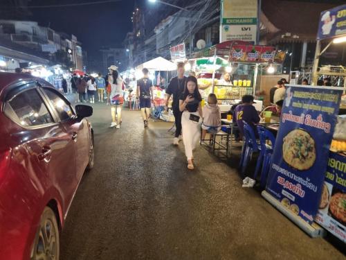 a woman walking down a street at a market at night at khampiane hotel in Ban Nongdouang