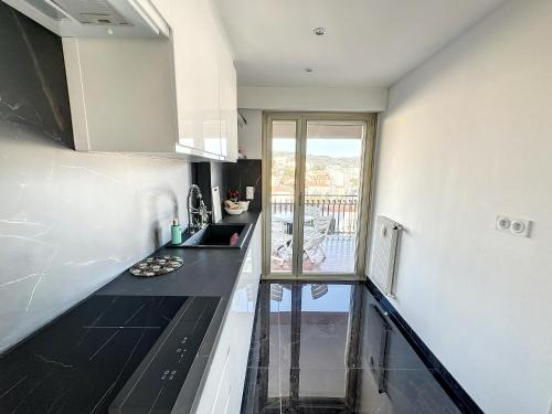 une cuisine avec des comptoirs noirs et une fenêtre dans l'établissement SUQ3 - Très beau 2 pièces avec terrasse, à Cannes