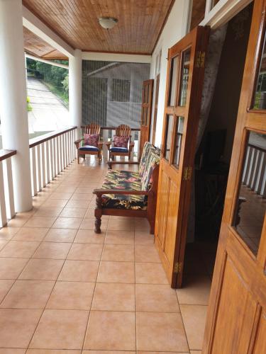 a porch with two chairs and a table at La Maison Hibiscus Self Catering Accommodation in Beau Vallon