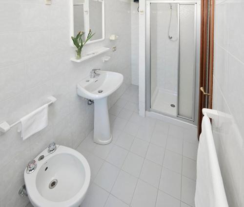 a white bathroom with a toilet and a sink at Hotel Bacco Rooms and Breakfast in Pietra Ligure