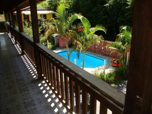 a balcony with a swimming pool with palm trees at Pousada Boliche in Palhoça