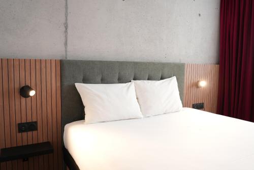 a bedroom with a bed with white pillows and red curtains at ibis Styles Lens Centre Gare in Lens