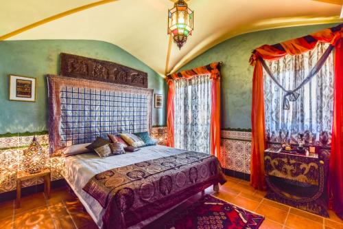 1 dormitorio con 1 cama, lámpara de araña y ventanas en Casa del Trotamundos, en Villamayor de Campos