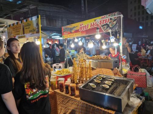 a group of people standing around a food stand at a market at Khampiane1 Hotel in Ban Nongdouang
