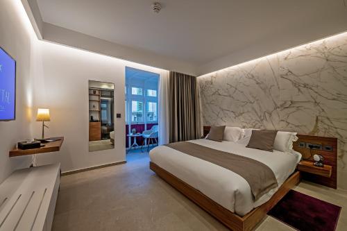 1 dormitorio con 1 cama grande y pared de mármol en The Capital Boutique Hotel, en La Valeta