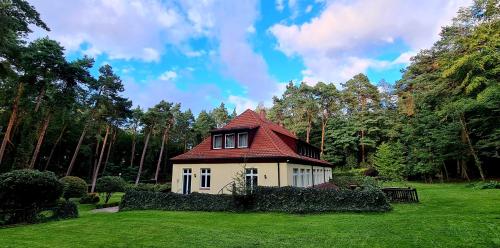a small house with a red roof in a yard at Pasjonat Tu in Tuczno