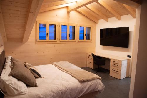 Dormitorio con cama, escritorio y TV en Chalet mit Kino und Jacuzzi in Gsteig b. Gstaad, en Gsteig