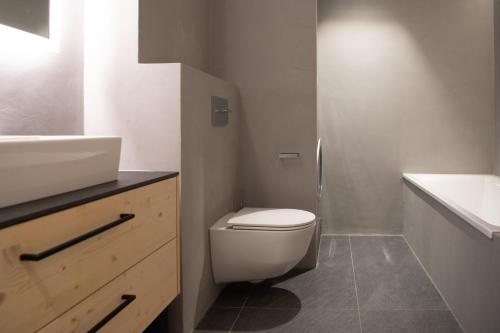 a bathroom with a white toilet and a sink at Chalet mit Kino und Jacuzzi in Gsteig b. Gstaad in Gsteig