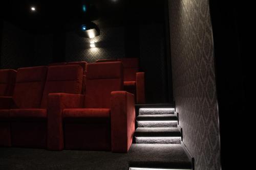 an empty theatre with a red couch and stairs at Chalet mit Kino und Jacuzzi in Gsteig b. Gstaad in Gsteig