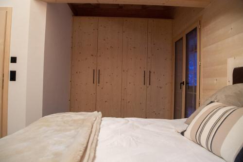 a bedroom with a white bed with wooden cabinets at Chalet mit Kino und Jacuzzi in Gsteig b. Gstaad in Gsteig